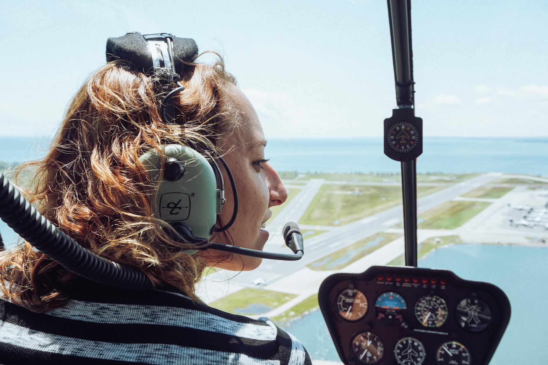 happy woman in headset sitting in cockpit during helicopter tour