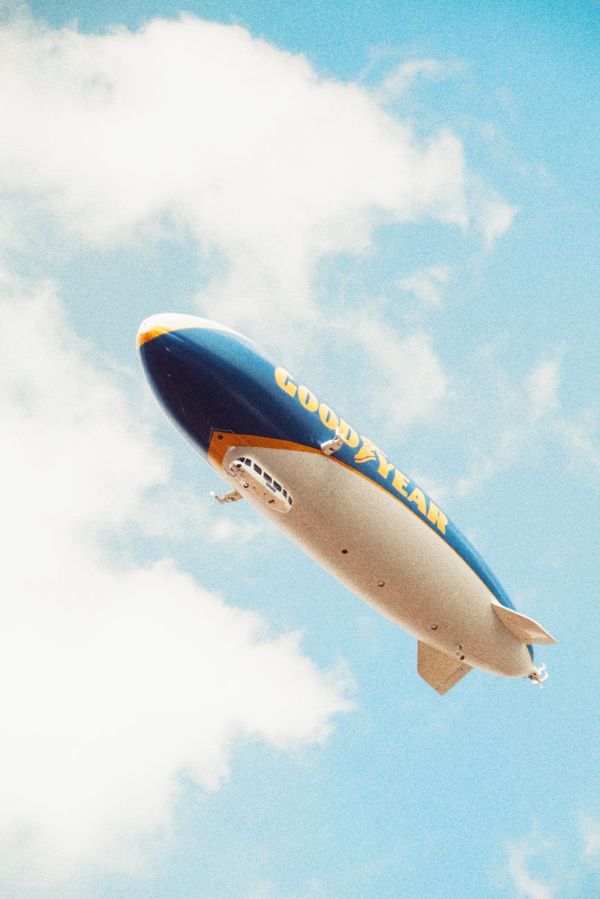 goodyear blimp in blue sky with clouds