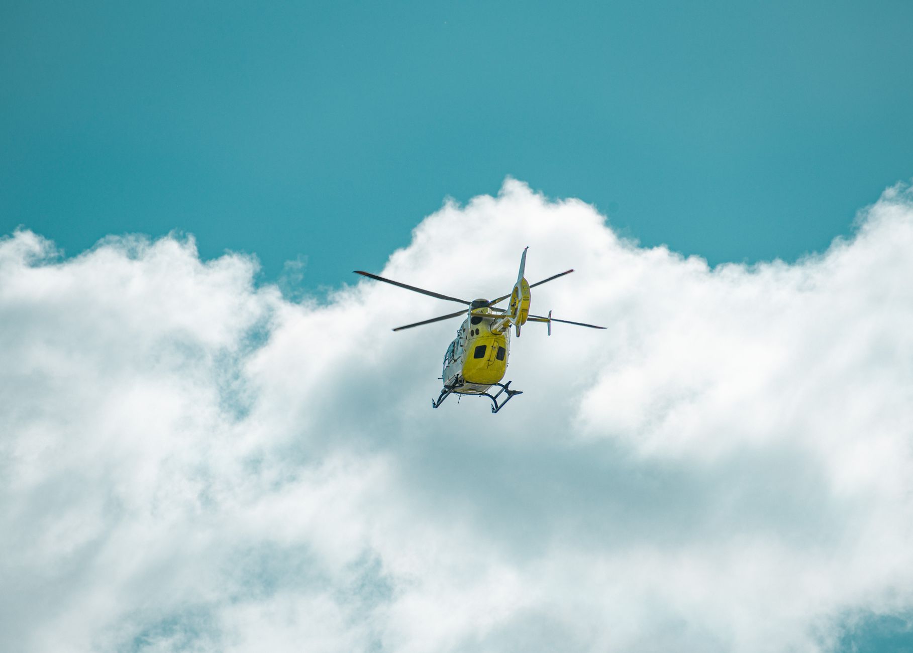 helicopter flying under white clouds